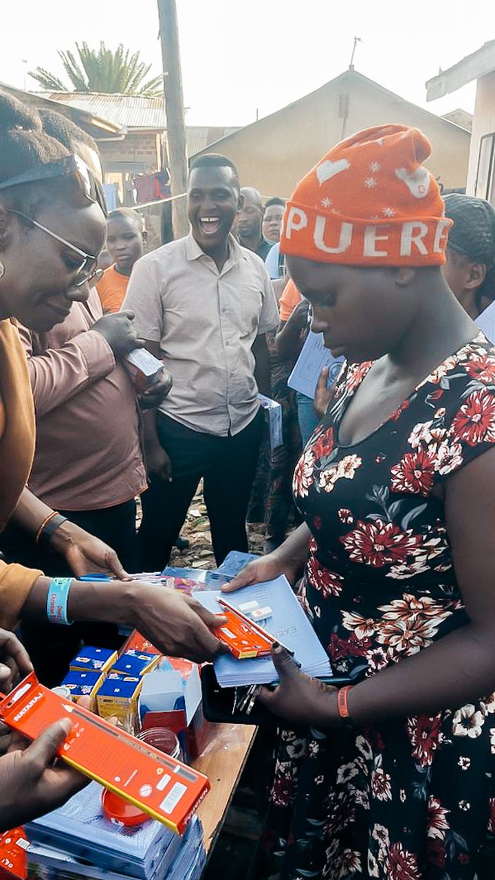 Tshani Foundation handing scholastic materials to a woman at a community outreach, 2026